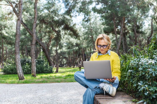 Woman using laptop amidst nature in a sunny day