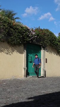 backpacker walking down scenic colonial street in antigua guatemala (backpacking latin america with large backpack) book bag back pack spanich architecture scenic tropical city