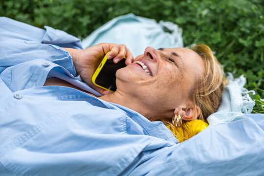 Woman relaxing outdoors on phone in natural setting