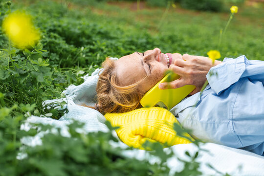 Woman relaxing outdoors with a phone call in the grass