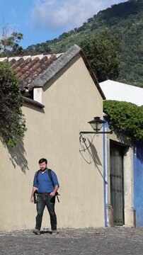 backpacker walking down scenic colonial street in antigua guatemala (backpacking latin america with large backpack) book bag back pack spanich architecture scenic tropical city
