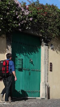 backpacker walking down scenic colonial street in antigua guatemala (backpacking latin america with large backpack) book bag back pack spanich architecture scenic tropical city