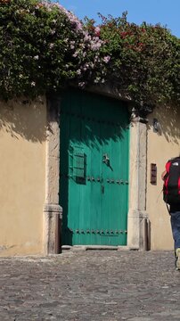 backpacker walking down scenic colonial street in antigua guatemala (backpacking latin america with large backpack) book bag back pack spanich architecture scenic tropical city