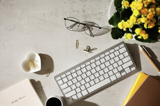 Feminine workspace with keyboard and planner on desk