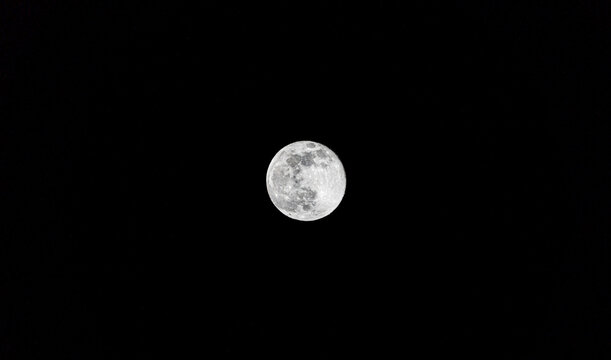 Full moon shining brightly in the starless night sky