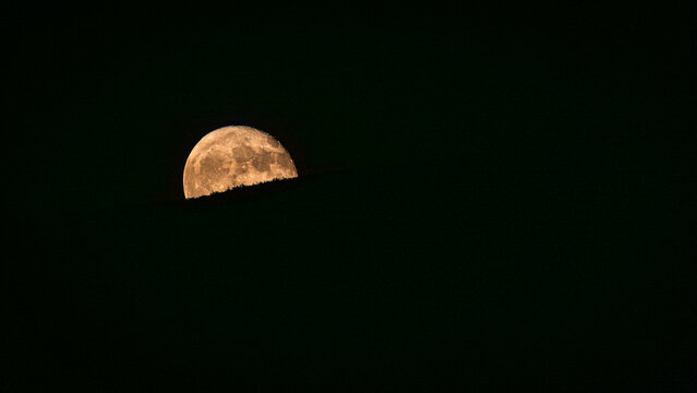 Moon partially hidden by dark horizon
