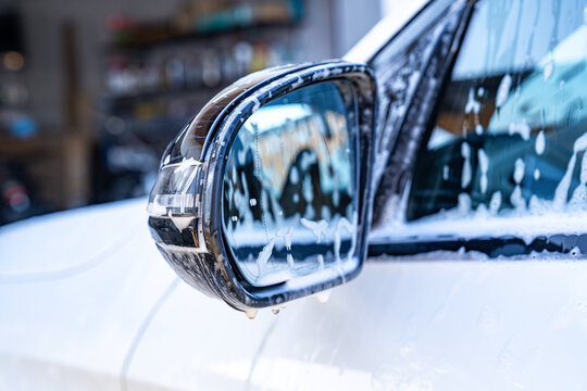 Close-up of soapy car side mirror during auto wash