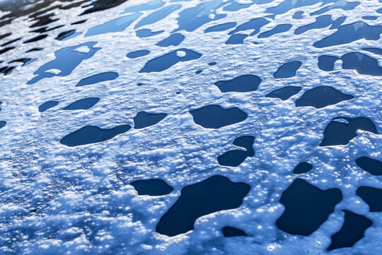 Soap foam and water droplets on car glass closeup background