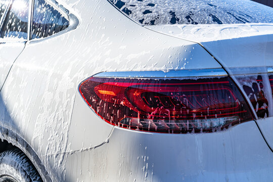 Close-up of white car being washed with soap foam
