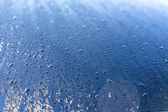 Raindrop texture on car glass with blue bokeh light