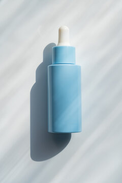 Minimal blue cosmetic serum bottle with dropper in sunlight
