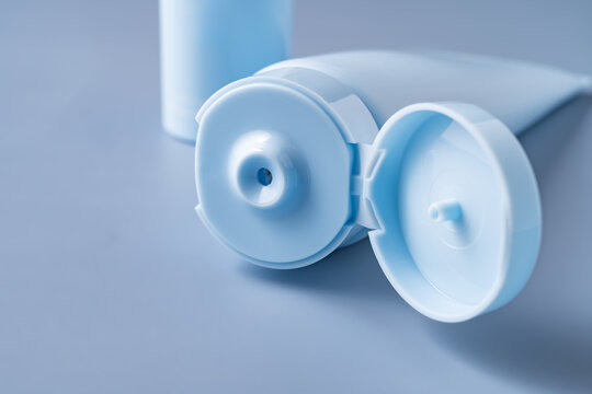 Cosmetic cream tube with open cap on blue background
