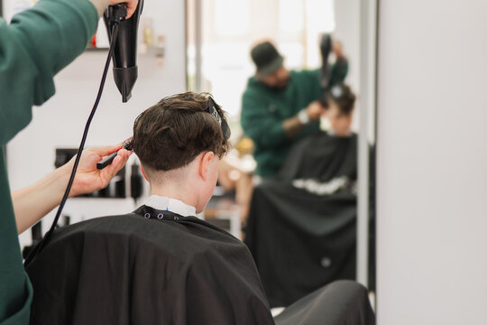 Boy getting dried haircut in modern barbershop salon