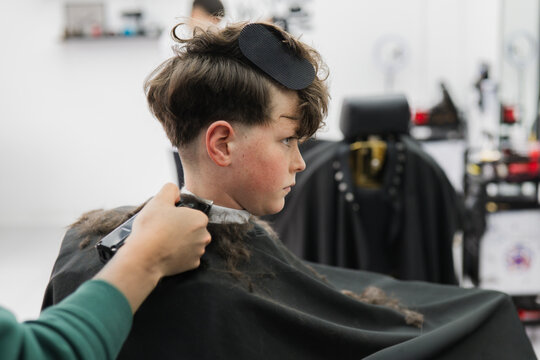 Boy getting a modern haircut with clippers in barbershop
