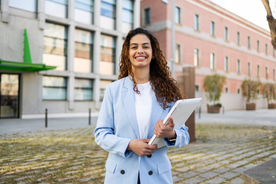 Smiling businesswoman with tablet outside modern office building