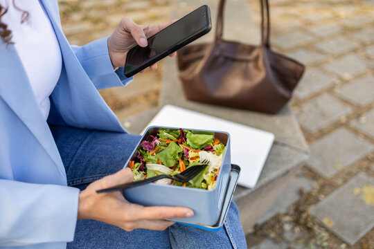 Businesswoman using smartphone during healthy lunch break