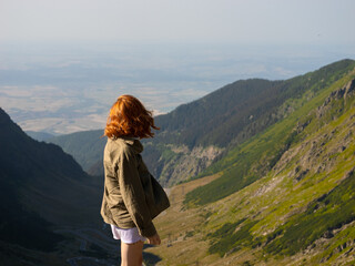 Obraz premium Two women enjoy breathtaking views of the Transfagarasan mountain route in Romania. Surrounded by lush green hills, they embrace the natural beauty of the landscape.