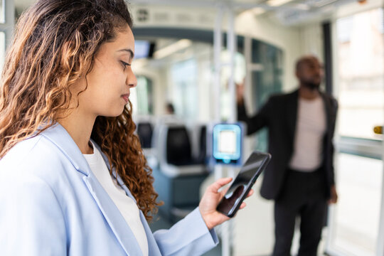 Business commuter using smartphone inside modern city tram