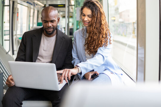 Business couple working on laptop while commuting by train