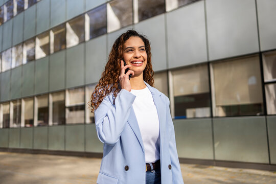 Smiling businesswoman making a phone call outside office
