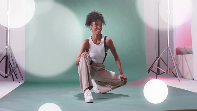 Woman performing routine on green backdrop for fashion, lights projecting bokeh causing her miming