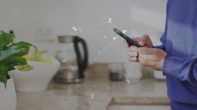 Senior male holding phone in kitchen tapping swiping moving network overlay in sync aligning tech