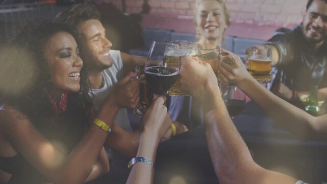 Group of adults bringing drinks in bar, centering beer mugs and wine glass for toast