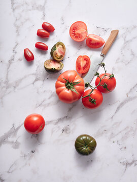 Fresh heirloom and cherry tomatoes on marble, top view