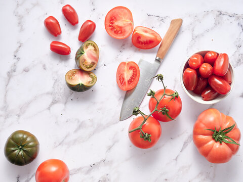 Fresh tomatoes and knife on marble countertop in bright kitchen