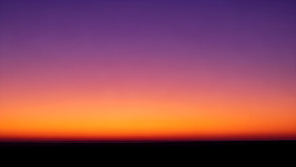 Fototapeta premium Vibrant orange and purple hues fill the sky during a serene sunset