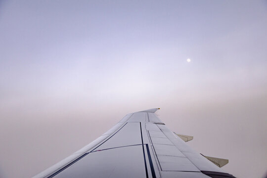 Airplane wing above soft cloud layer at calm sunrise light