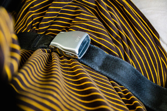 Airplane seat belt buckle on striped shirt close-up