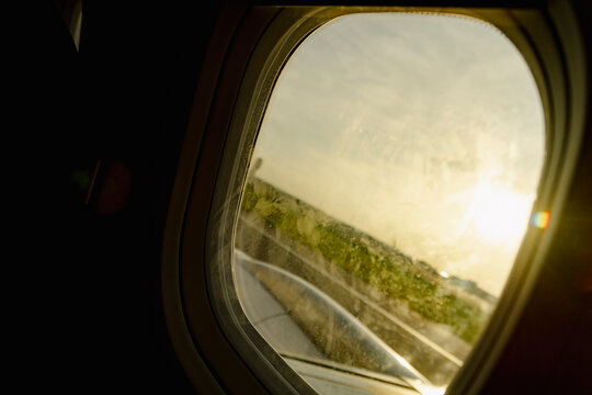 Airplane window view during takeoff with warm sunrise light
