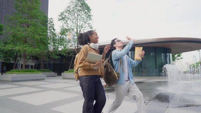 Latino male and African female students walking on campus outdoors. 