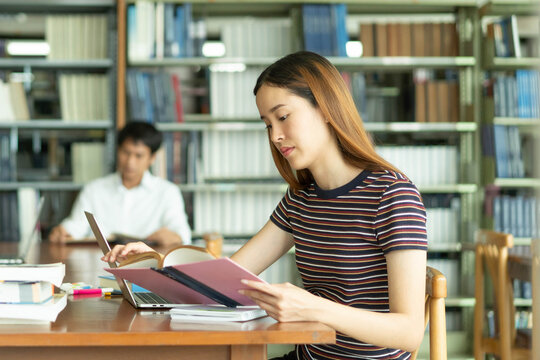 Female asian student studying and reading book in library