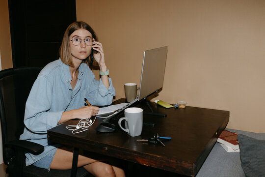 Woman working from home at desk with laptop and phone call