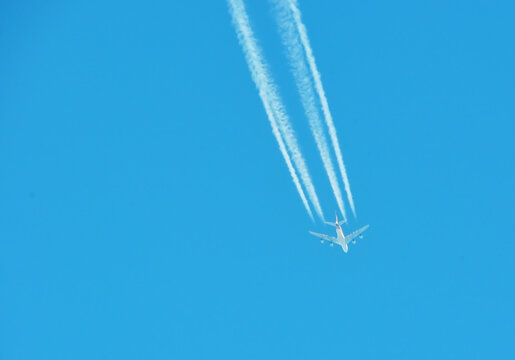 Airplane with contrail in clear blue sky