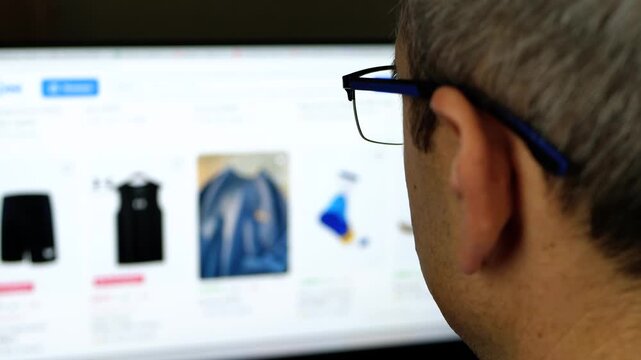 Man browsing clothing online on laptop at home. Digital shopping experience highlights ecommerce, consumer behavior and convenience of choosing fashion items in modern online retail environment.