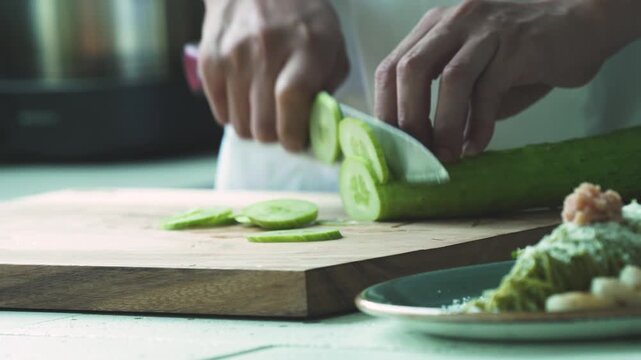 Cutting Fresh Cucumber with Knife on Board