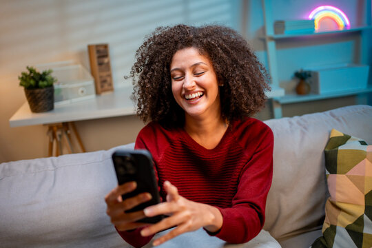 Attractive Latina woman using phone video call at night time in house.