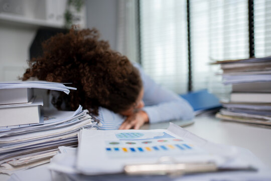 Exhausted young Latina businesswoman overworking late at the office. 