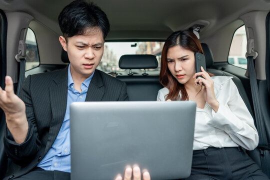 Frustrated Asian busy businessman and woman sit in back seat of a car. 
