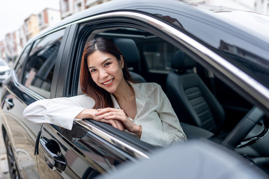 Portrait of Asian woman sitting inside vehicle and looking at camera. 