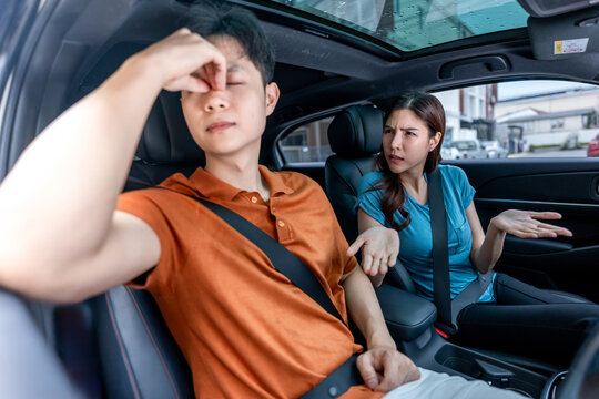 Asian young man and woman sitting inside a car, arguing while driving.