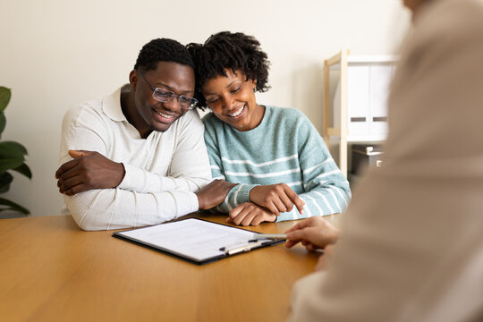 Happy couple evaluating contract terms with financial advisor in office