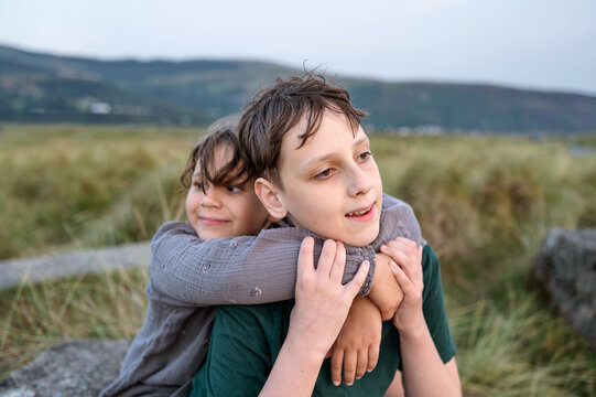 Sister hugging brother from behind sharing joyful outdoor moment