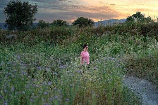 Woman walks through the countryside at sunset