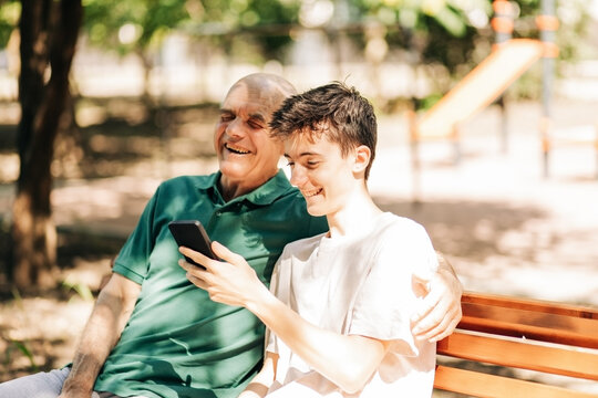 Happy grandfather and grandson laughing together over smartphone