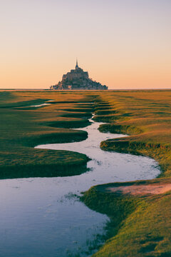 Mont Saint Michel at sunset with winding tidal stream Normandy
