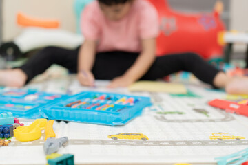 Obraz premium Selective focus on colorful crayons with a blurred child playing in the background